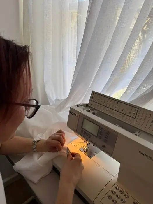 Professional hemming of linen curtains during on-site height adjustment